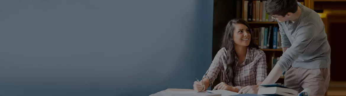 A dark background image of a tutor helping a student at a library